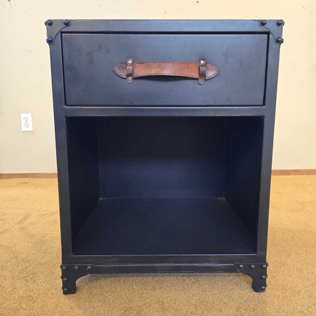 Black nightstand with a leather handle on a beige carpeted floor.