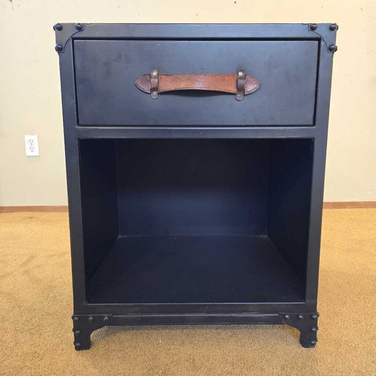 Black nightstand with a leather handle on a beige carpeted floor.