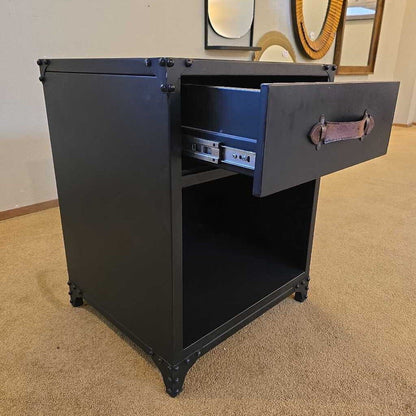 Black metal cabinet with open drawer on a carpeted floor