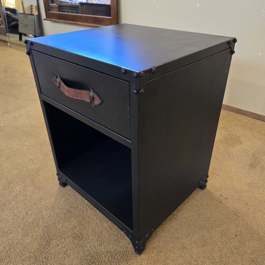 Black metal nightstand with a drawer on a beige carpeted floor.