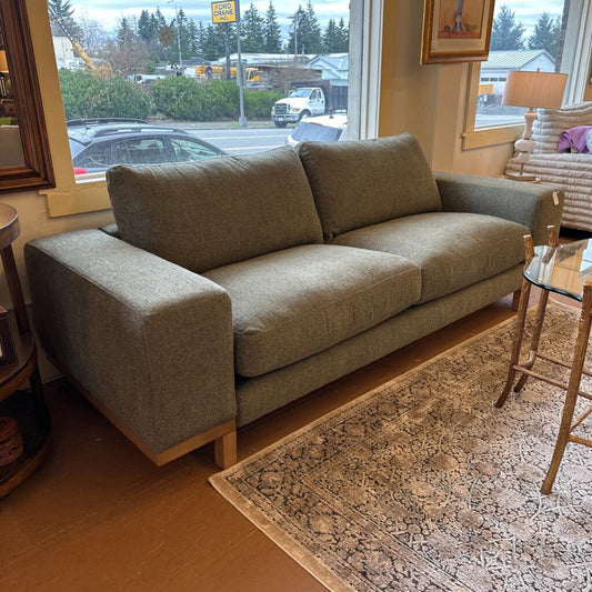 Brown sofa in a room with a window view of a parking lot.