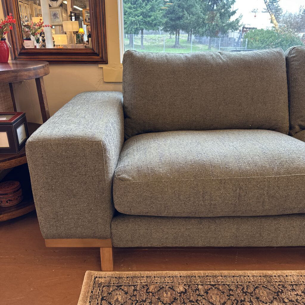 Brown sofa in a living room setting with a window and decor in the background.