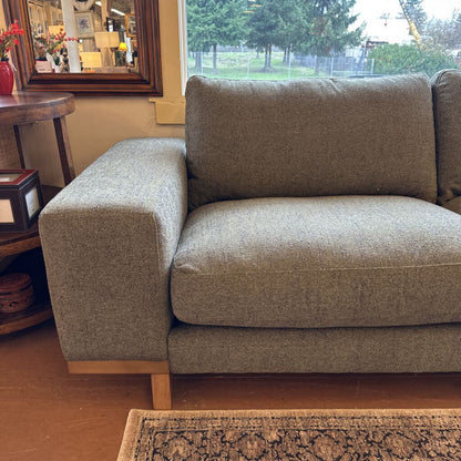 Brown sofa in a living room setting with a window and decor in the background.