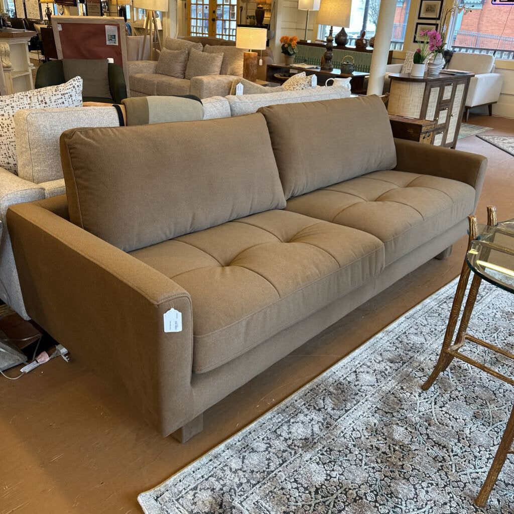 Beige sofa in a showroom with other furniture and decor items.