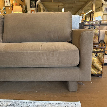 Beige sofa in a store setting with various items in the background
