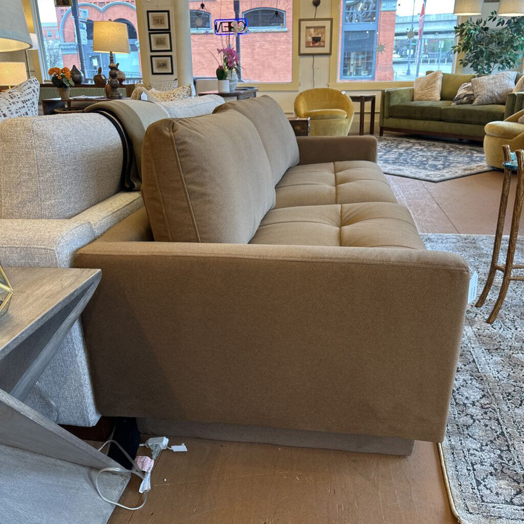 Beige sofa in a living room setting with furniture and decor.