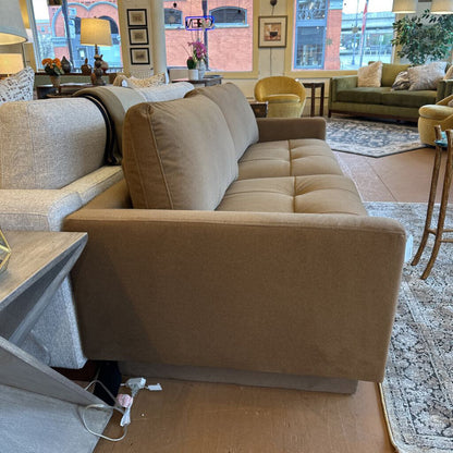 Beige sofa in a living room setting with furniture and decor.