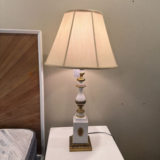 Decorative table lamp with a white base and gold accents on a surface.