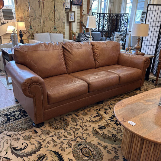 Brown leather sofa in a room with decorative elements and furniture.