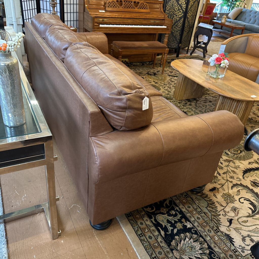 Brown leather sofa in a room with a piano and decorative items.