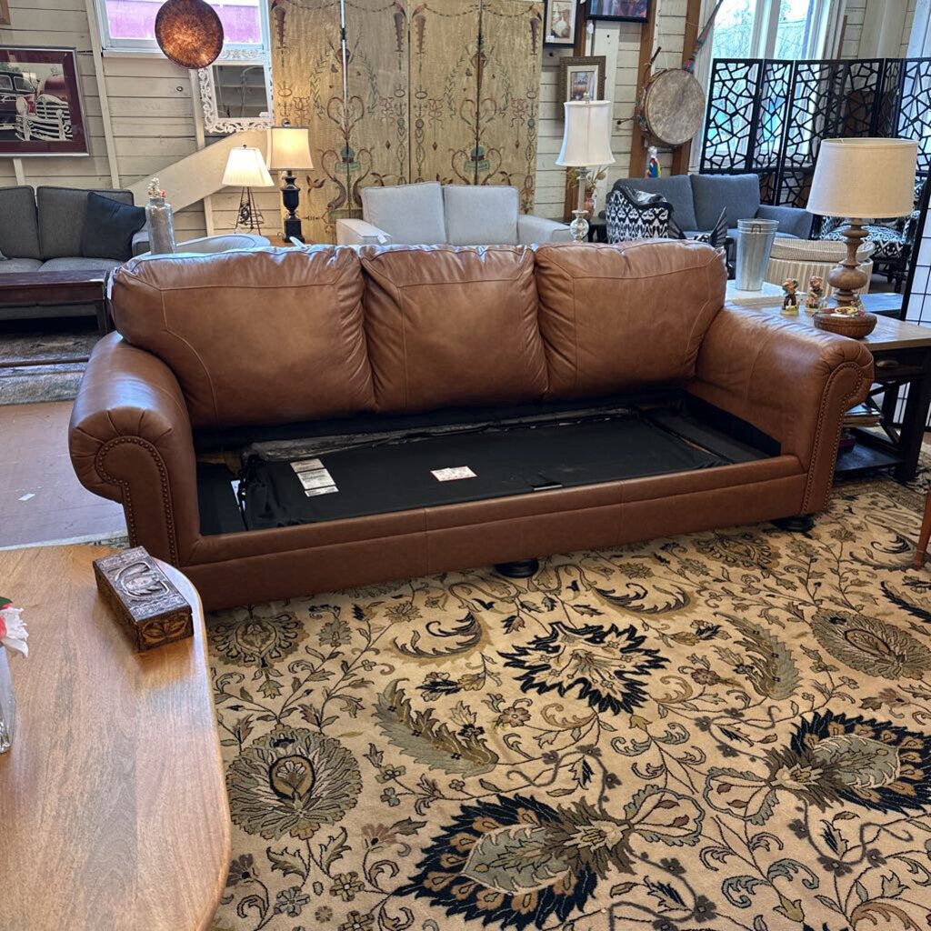 Brown leather sofa with a black mat underneath in a living room setting.