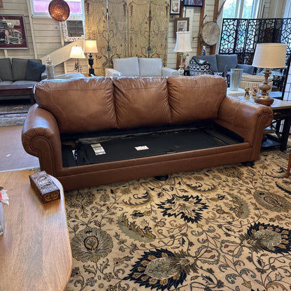 Brown leather sofa with a black mat underneath in a living room setting.