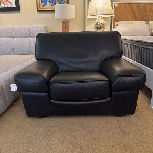 Black leather recliner chair in a room with gray sofa and lamps.
