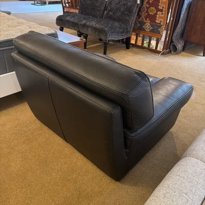 Brown leather sofa in a room with carpeted floor and furniture.
