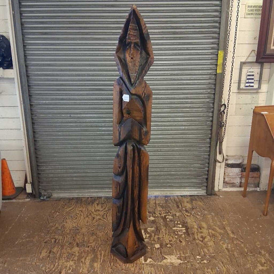 Wooden sculpture in front of a metal shutter