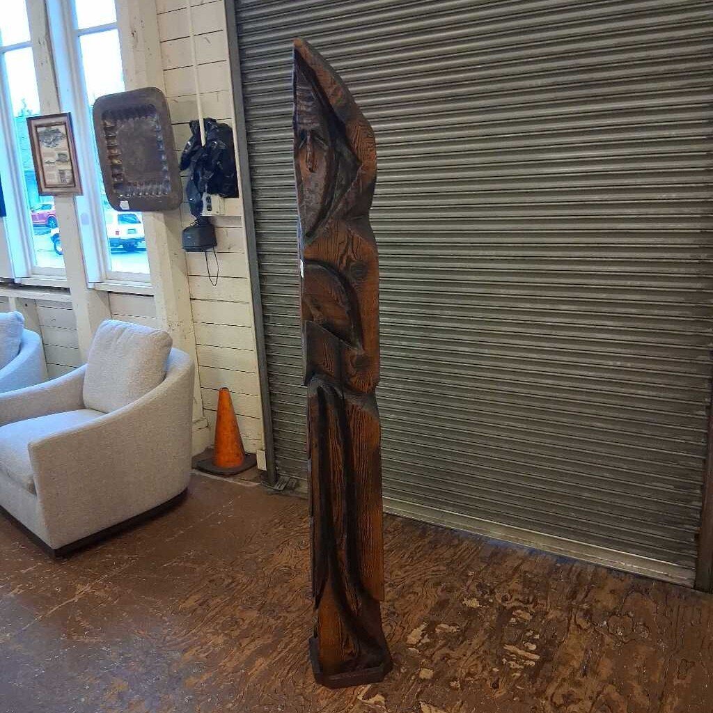 Wooden sculpture in a room with a window and furniture