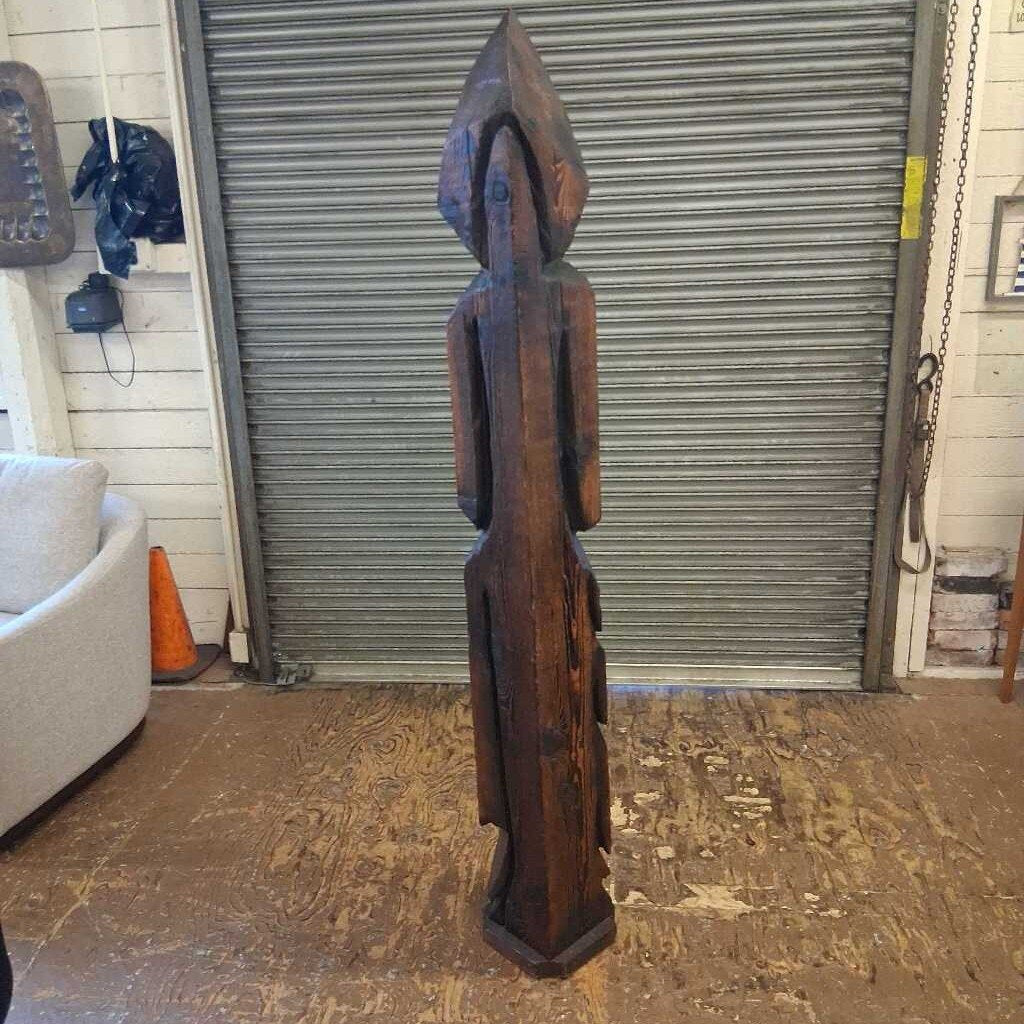 Wooden sculpture in a room with a metal shutter door.
