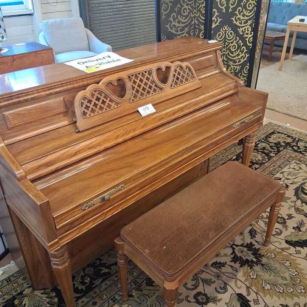 Wooden piano with a bench on a patterned rug in a room setting