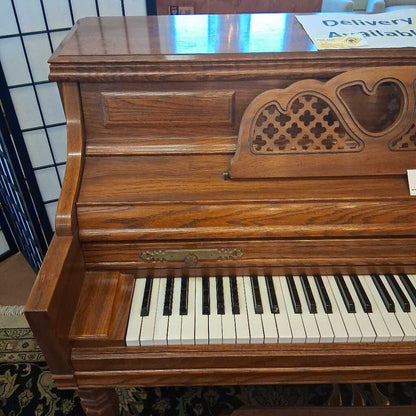 Wooden piano with decorative front panel in a showroom setting
