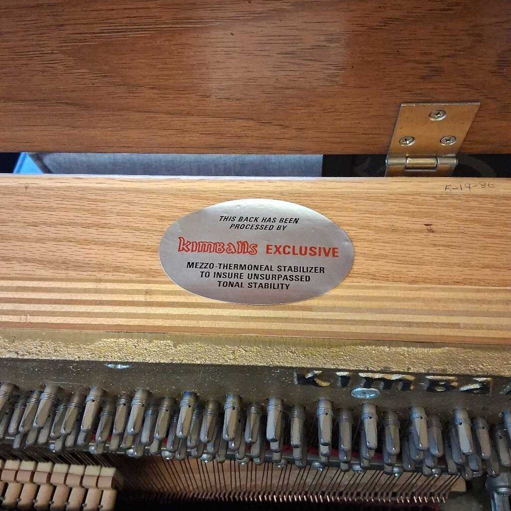Close-up of a piano with a Kawai label on the back, showing the strings and wooden casing.