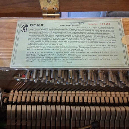 Kimball piano warranty card inside a piano with keys visible
