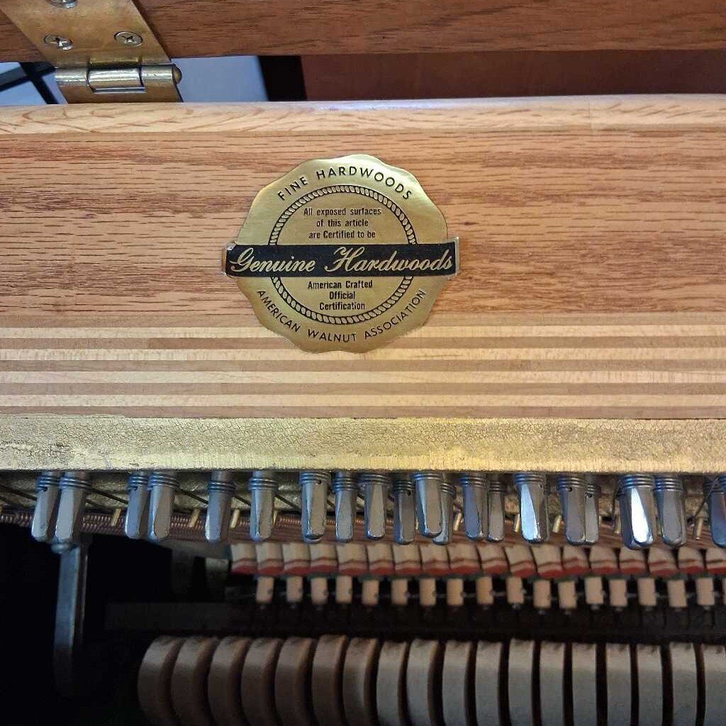 Wooden surface with a 'Genuine Hardwoods' label and piano strings below.