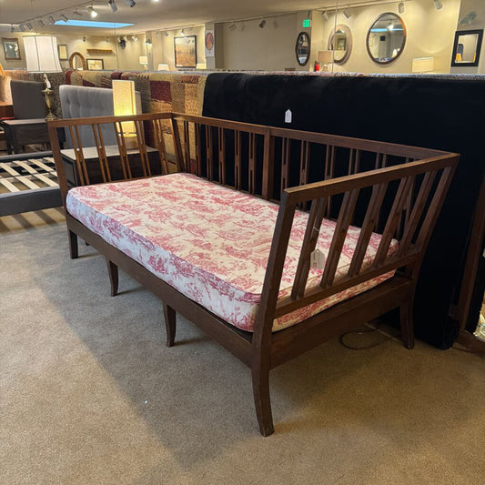 Wooden bed frame with floral mattress cover in a showroom setting
