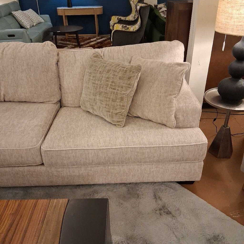 Beige sectional sofa with patterned cushions in a living room setting.