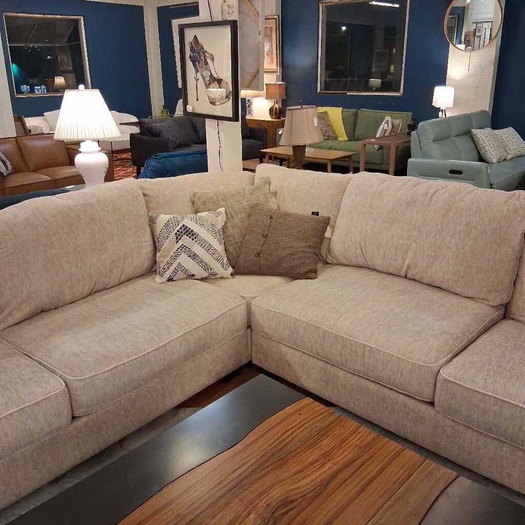 Beige sectional sofa with decorative pillows in a showroom setting