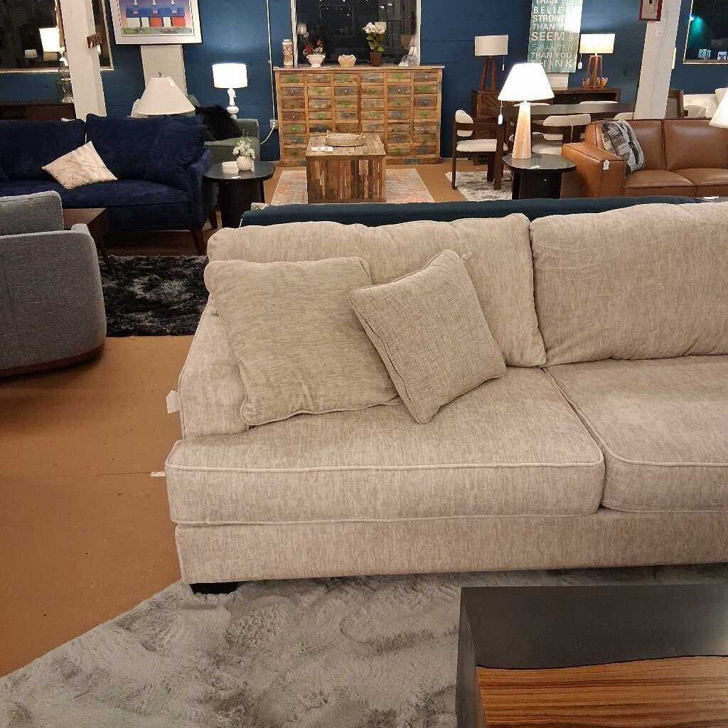 Beige sectional sofa with cushions in a living room setting