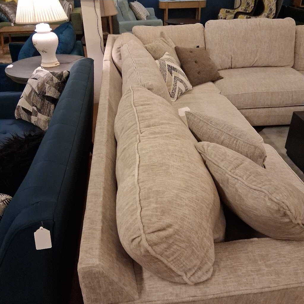 Beige sectional sofa with decorative pillows in a furniture store setting