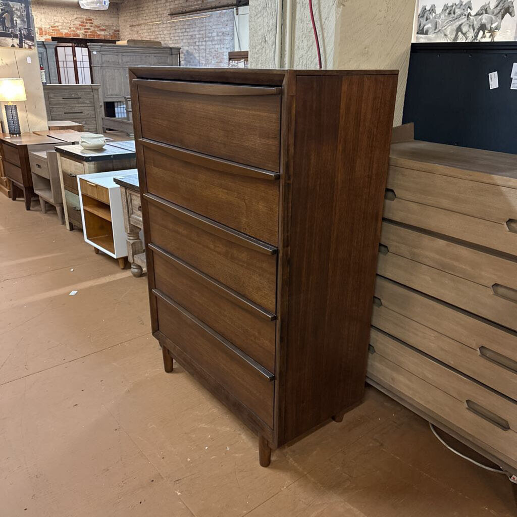 Wooden dresser in a showroom setting with other furniture pieces.