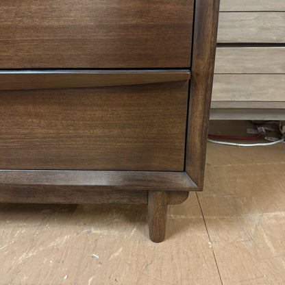 Wooden dresser with a focus on the base and legs on a wooden floor.