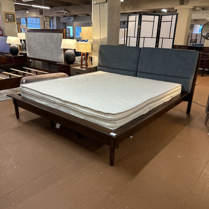 Bed with wooden frame and gray mattress in a showroom setting