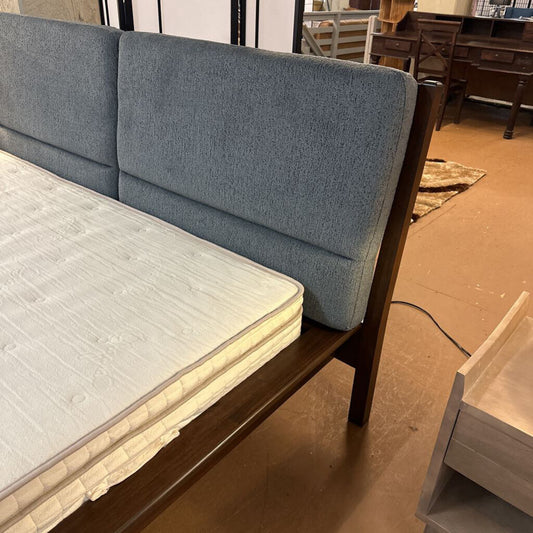 Blue upholstered bed frame with mattress in a room setting