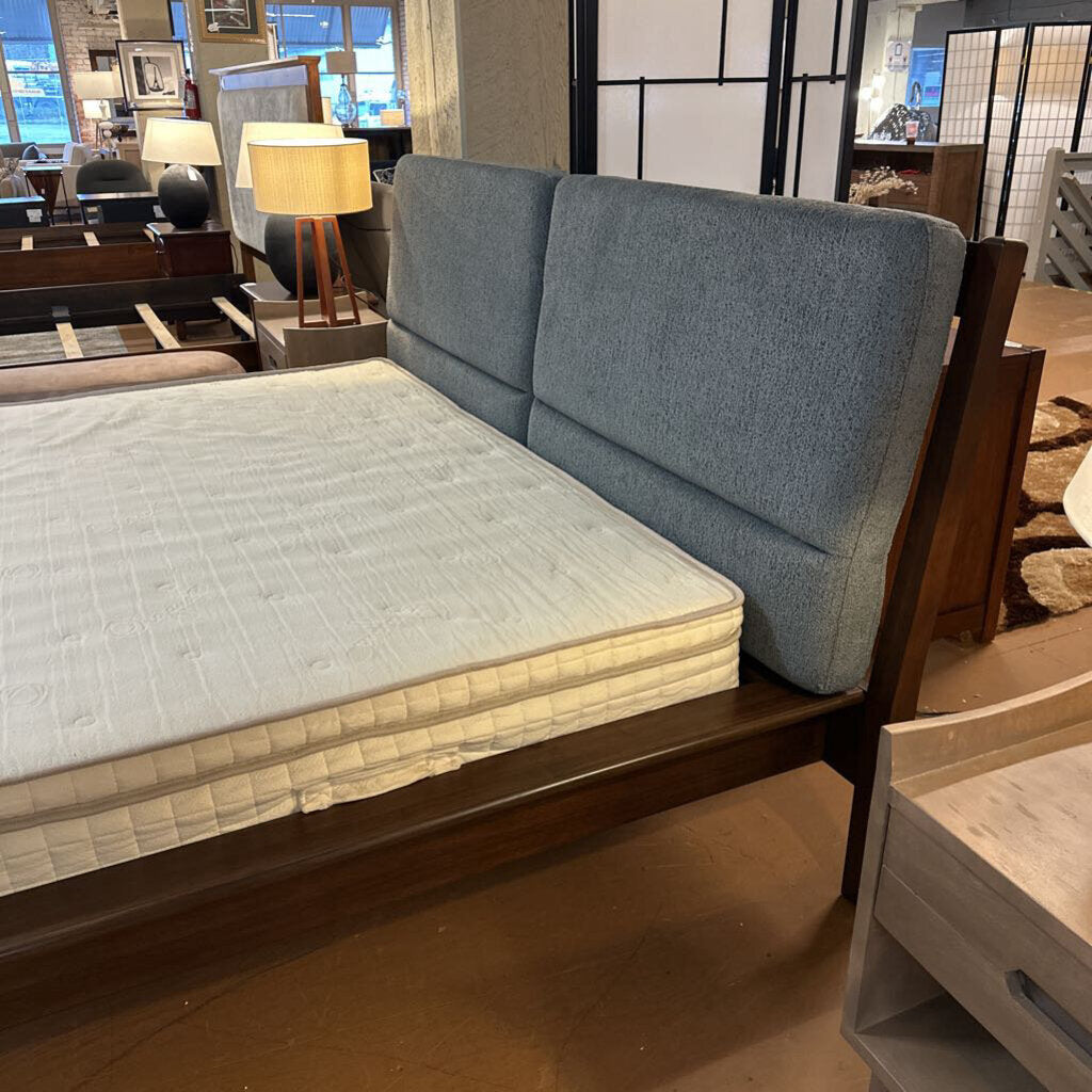 Gray upholstered bed with wooden frame in a showroom setting