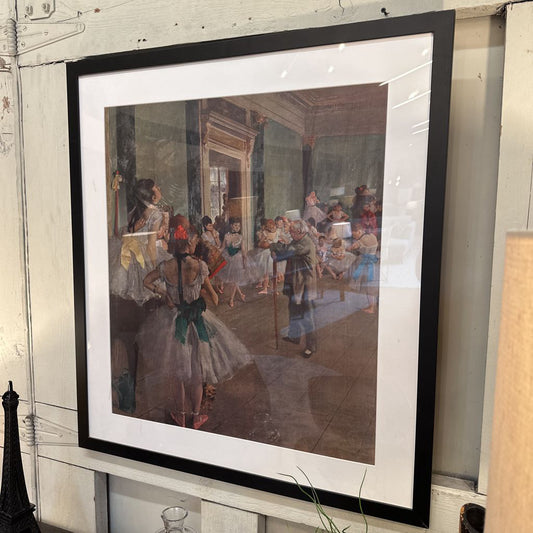 Framed painting of a dance class by Edgar Degas on a wall.