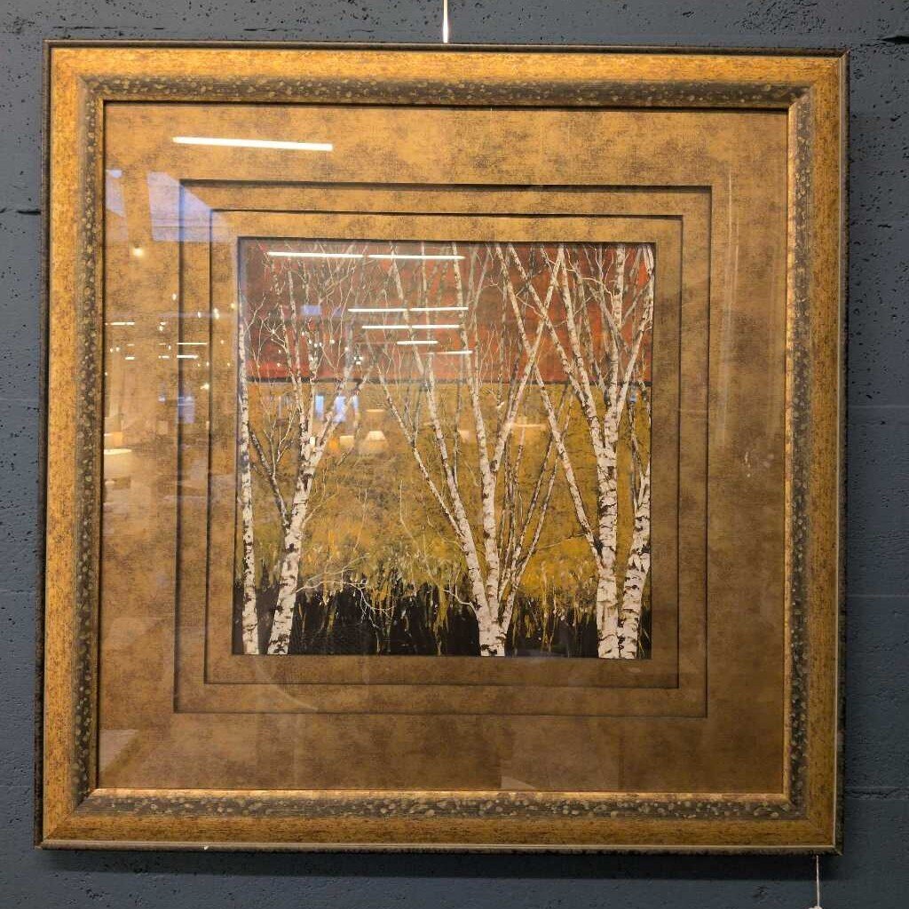 Framed artwork of trees with a gold frame on a dark background