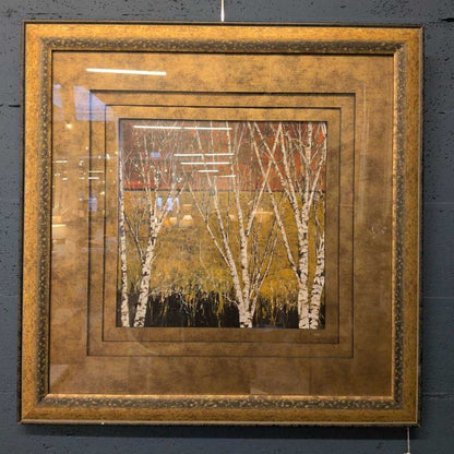Framed artwork of trees with a gold frame on a dark background