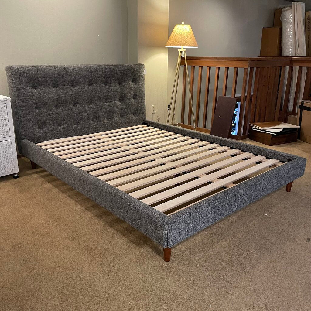 a speckled grey tufted fabric bed frame with blond wooden slats and dark wooden legs