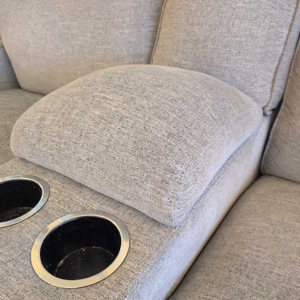 Gray fabric sofa with two round metal coasters on a cushion.
