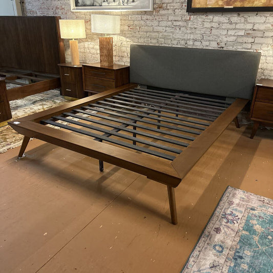 Wooden bed frame with metal slats on a wooden floor.