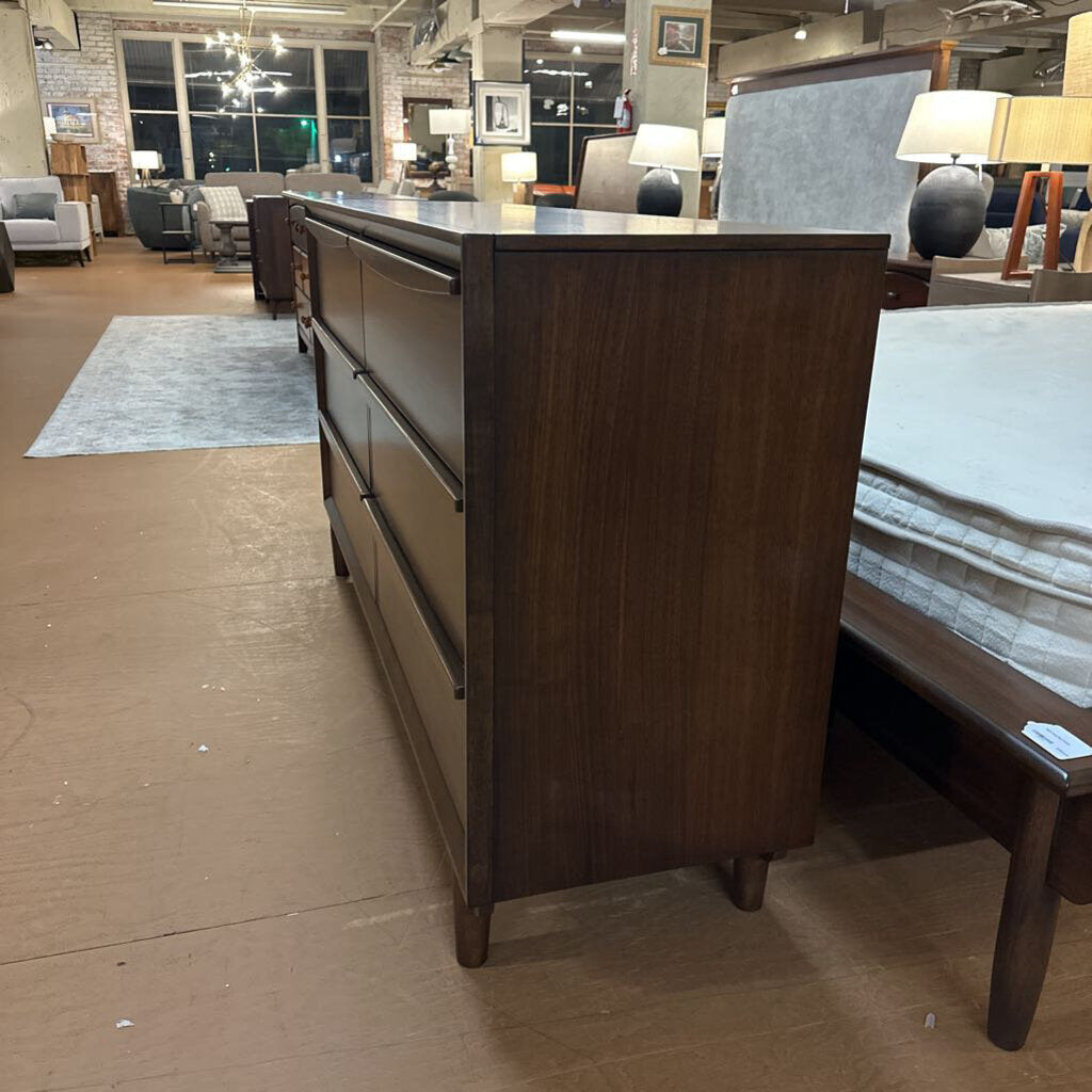 Wooden dresser in a furniture store setting with other items in the background
