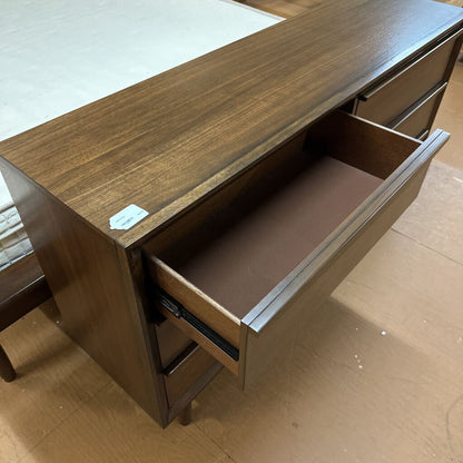 Wooden desk with an open drawer on a wooden floor