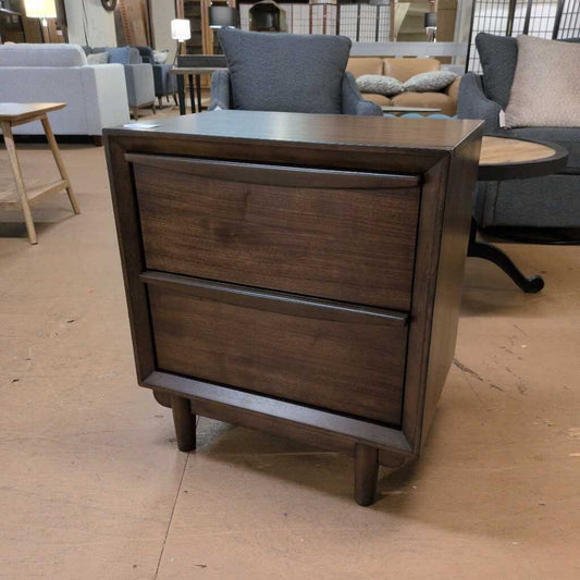 Wooden nightstand with two drawers in a furniture store setting