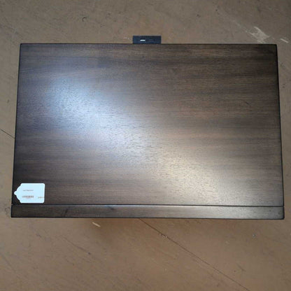 Dark wooden box with a label on a beige surface