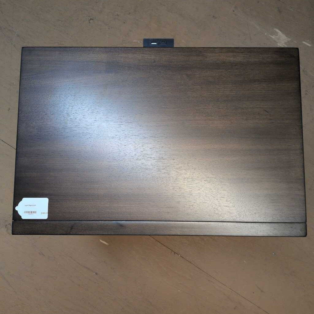 Dark wooden box with a label on a beige surface