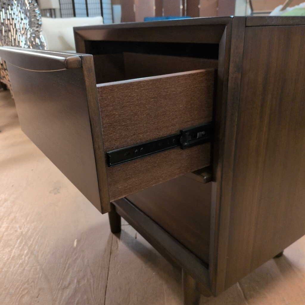 Wooden drawer unit with an open drawer on a wooden floor.