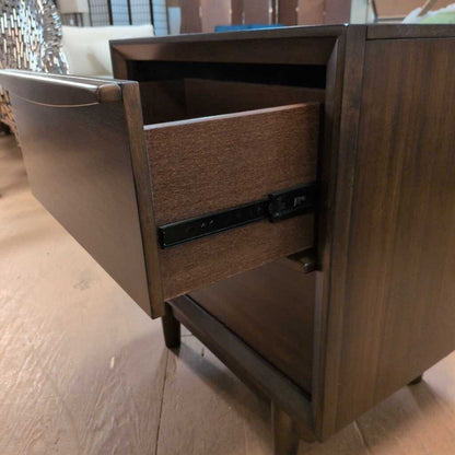 Wooden drawer unit with an open drawer on a wooden floor.