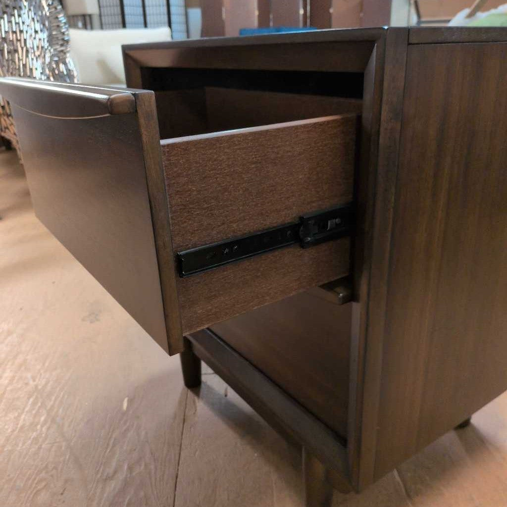 Wooden drawer unit with an open drawer on a wooden floor.